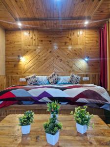 a bedroom with a large bed with two potted plants at Ananta Valley Home's in Kulu