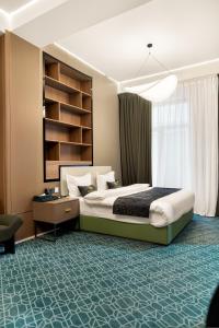 a bedroom with a bed and a desk and a window at NOOMA Hotel Aitmatova in Bishkek