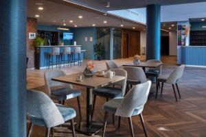 a restaurant with tables and chairs and a bar at DOMITYS - Les Canotiers in Argenteuil
