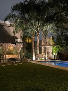 a backyard with a pool and palm trees at night at Armonium Airport in Ezeiza