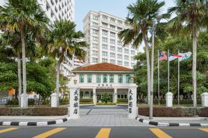 a building with palm trees in front of a street at The Majestic Malacca, Melaka - Small Luxury Hotels of the World in Malacca