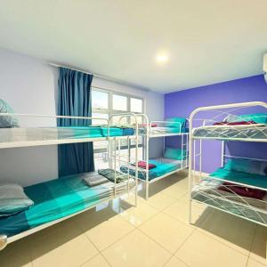 a room with three bunk beds and a purple wall at KULAI IOI MALL D'Putra Suites Near JPO Senai Airport in Kampong Saleng