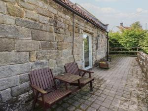 two wooden chairs sitting next to a stone wall at Horseshoe Cottage in Middlesbrough