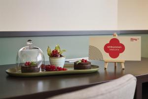 a table with a plate of cakes and a sign at iStay by NH Berlin City Ost Hotel in Berlin