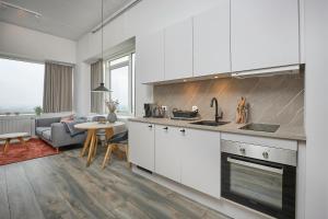 a kitchen with white cabinets and a living room at World Trade Center Ballerup - Forenom in Ballerup
