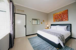a bedroom with a bed and a painting on the wall at The Lavana Signature Villa Alessa Puncak in Puncak +22 photos