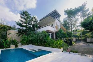 a house with a swimming pool in front of a house at The Lavana Signature Villa Alessa Puncak in Puncak