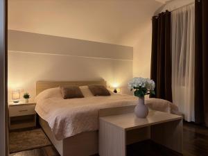 a bedroom with a bed and a vase of flowers on a table at Croatia Palace - Ravna Gora in Ravna Gora