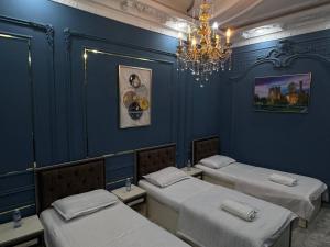 a blue room with three beds and a chandelier at Abubakir Guests House in Samarkand