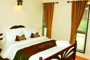 a bedroom with a bed and a window at Baan Buapatumma in Mae Sai