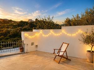 a chair sitting on a patio with a wall with lights at Papa-Antonis Stone House in Zaros