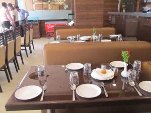a table in a restaurant with white plates and glasses at Venkat Presidency in Navi Mumbai