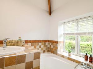 a bathroom with a tub and a sink and a window at Lumford Mill Cottage in Bakewell +23 photos