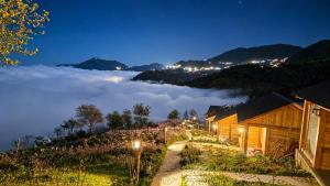 a view of a foggy mountain at night with a house at Samu Retreat Tà Xùa in Bắc Yên