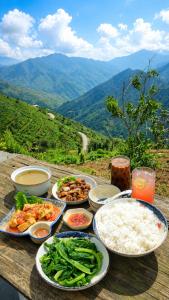 a table with plates of food on a table with mountains at Samu Retreat Tà Xùa in Bắc Yên