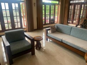 a living room with a couch and a chair and windows at Neem Homestay in Hatton
