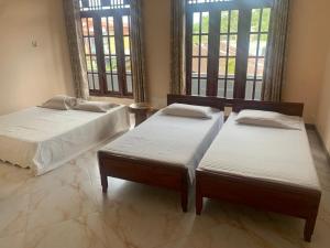 two twin beds in a room with two windows at Neem Homestay in Hatton