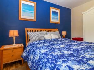 a blue bedroom with a bed and a nightstand with two lamps at Pen Glorian in Conwy