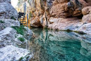 a pool of water in a canyon with rocks at El Hortal i lloo in El Cuervo