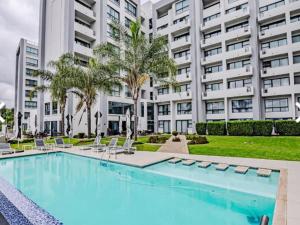 a swimming pool in front of a large building at Cosy Regency menylin apartment in Pretoria