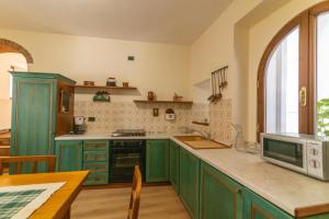 a kitchen with green cabinets and a table with a microwave at Spacious home near Orta, 8min in Armeno