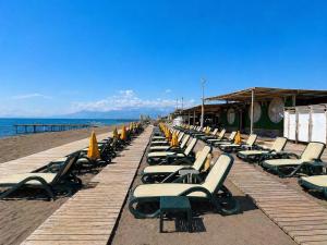 a row of lounge chairs and umbrellas on a beach at Arya Apart Kundu Hotel in Lara