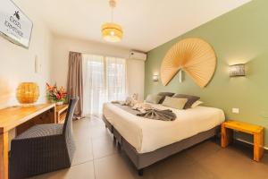 a bedroom with a bed with a desk and a chair at Hôtel Exsel Ermitage in Saint-Gilles-les-Bains +19 photos