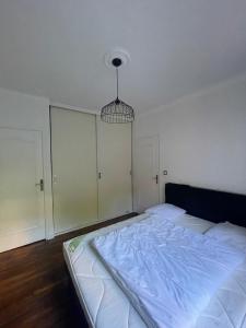 a white bedroom with a large bed and a chandelier at Le Rennes Gare in Rennes