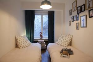 a living room with two beds and a window at Stylish Central Flat, Steps to Beach in Ostend