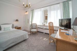 a bedroom with a bed and a desk and a television at Grand Hotel Cravat in Luxembourg