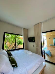 a bedroom with a large bed with a large window at The Town Pool Villas in Krabi