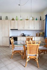 a kitchen with a glass table and wooden chairs at La SyRosA in Vári