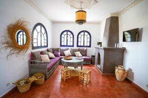 a living room with a purple couch and a fireplace at Maison d'hôtes Villa Latifa Essaouira in Essaouira