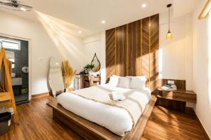 a bedroom with a large white bed and wooden floors at The Morris Central Hotel - O'TEL in Da Lat