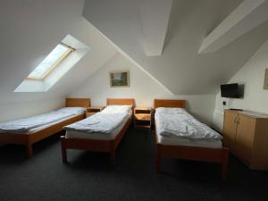 a attic room with two beds and a television at Penzion U Kašných in Mníšek pod Brdy