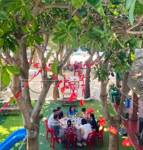 a group of people sitting at a table under trees at Hoa Bien Motel in Ly Son