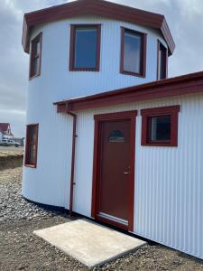 a large white garage with a red door at Svalbarð guesthouse in Hvammstangi +25 photos