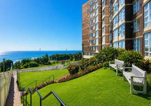 a park with benches and the ocean in the background at Scottburgh Peacehaven Holiday Flat 202 in Scottburgh
