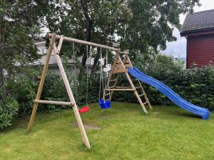 a wooden swing set with a blue slide at Spacious Villa in Lillehammer in Lillehammer