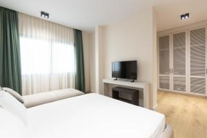 a white bedroom with a bed and a television at Pauz Hotel in Himare