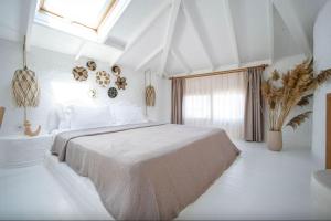 a white bedroom with a large bed and a window at Kurabiye Hotel in Alaçatı
