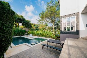 a swimming pool with a bench in a yard at The Lavana Signature Villa Herrera Puncak in Puncak