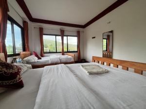 a bedroom with two beds and two windows at Hotel PeaceFul in Bandipur