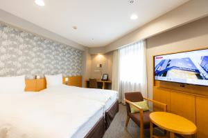 a hotel room with a bed and a flat screen tv at Richmond Hotel Sapporo Ekimae in Sapporo