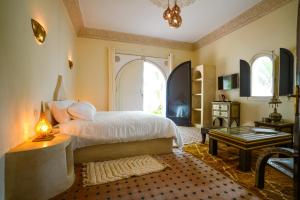 a bedroom with a bed and a table and a window at Maison d'hôtes Villa Latifa Essaouira in Essaouira +130 photos