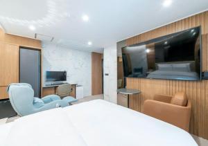 ein Hotelzimmer mit einem großen Bett und einem Fernseher in der Unterkunft Rosy Hotel in Cheongju