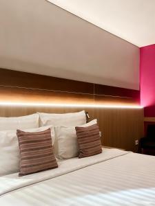 a bed with white pillows and a pink wall at Ra Premiere Simatupang in Jakarta