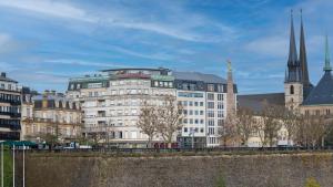 a large white building with a church in the background at Grand Hotel Cravat in Luxembourg