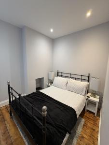 a bedroom with a black bed and a white wall at FRESH Flat in Leek, Staffordshire in Leek
