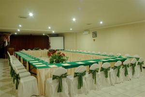 une grande table avec des chaises blanches et des arcs verts dans l'établissement Swaloh Resort & Spa, à Kalangbret